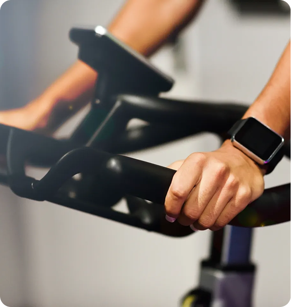 Hands gripping stationary bike handlebars.