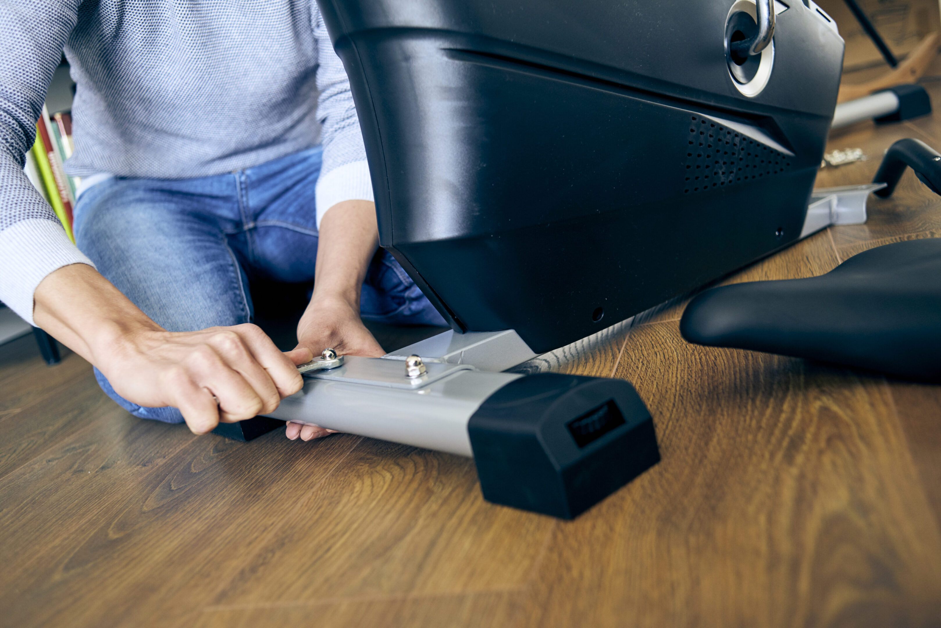 Person assembling stationary exercise bike at home.
